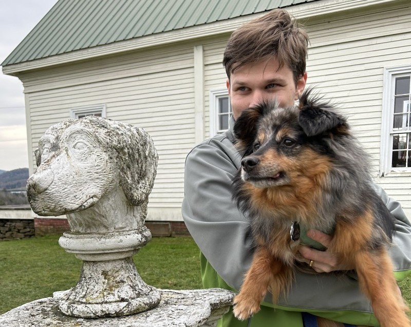A picture of me, Bryce, holding my dog jackie next to a statue of a dog's head, all of us looking in the same direction
