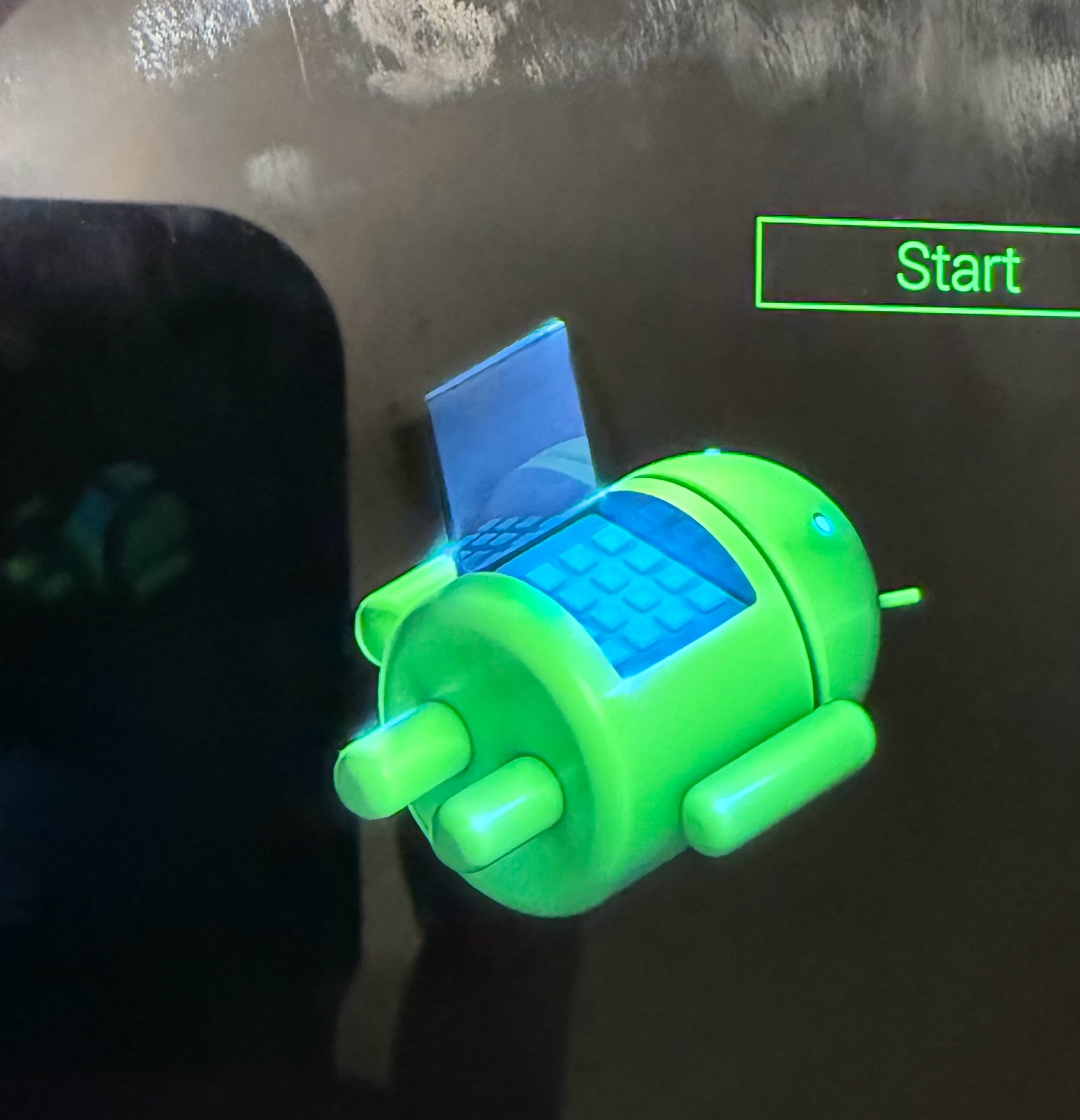 The green android mascot depicted laying down, with the abdominal region opened to reveal a mirrored blue interior with circuitry